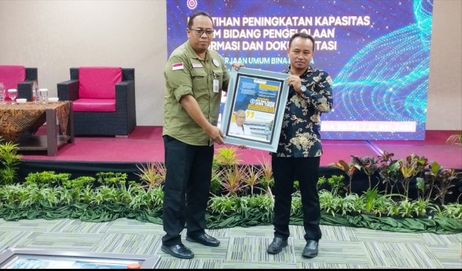 Direktur JatimTIMES Network Heryanto (kanan) memberikan cinderamata infografis kepada DPUBM Prov Jatim (foto: Hendra Saputra/JatimTIMES)